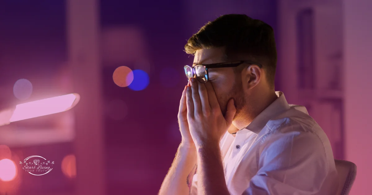 Stressed man in office, hands on face.