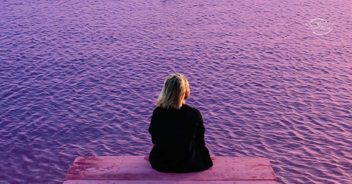 Woman alone on pink dock watching water