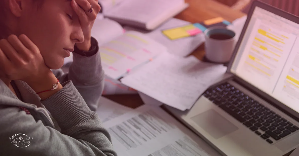 Stressed student studying with laptop and notes.