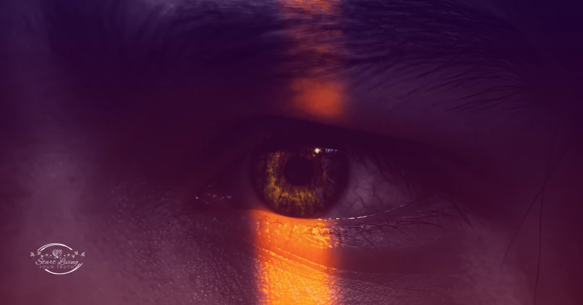Close-up of an eye with orange light reflection.