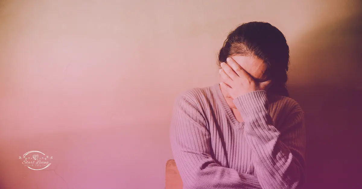 Woman in sweater covering face, feeling distressed.