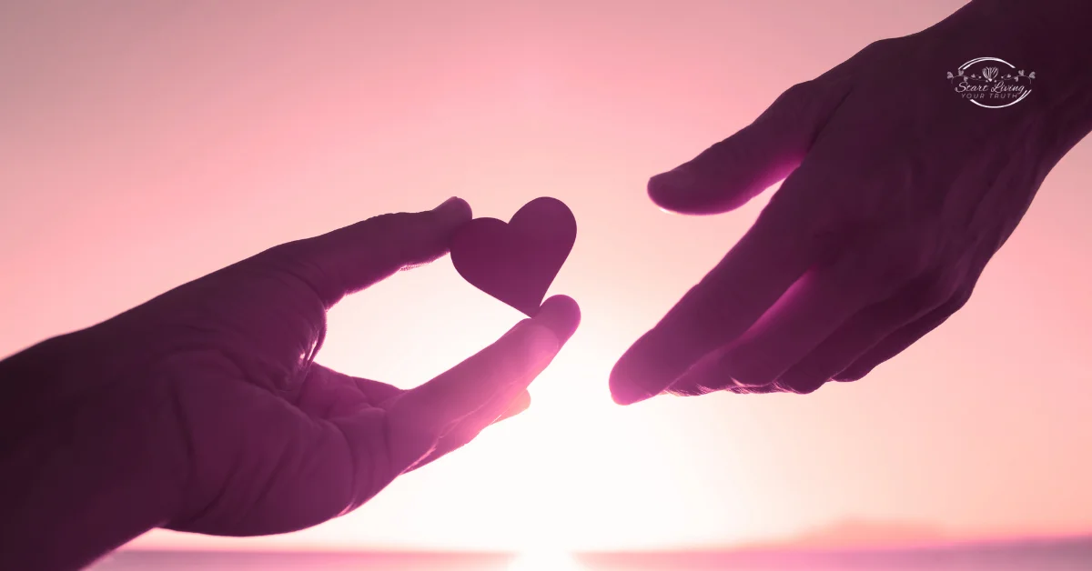 Silhouette hands passing heart at sunset.