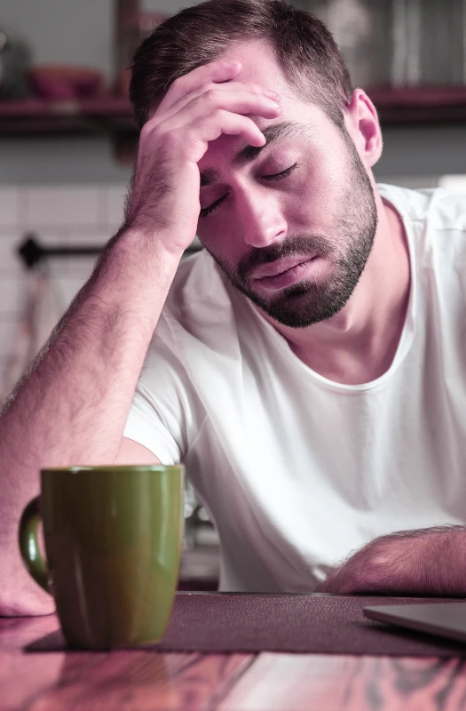 Tired man with coffee cup at table.