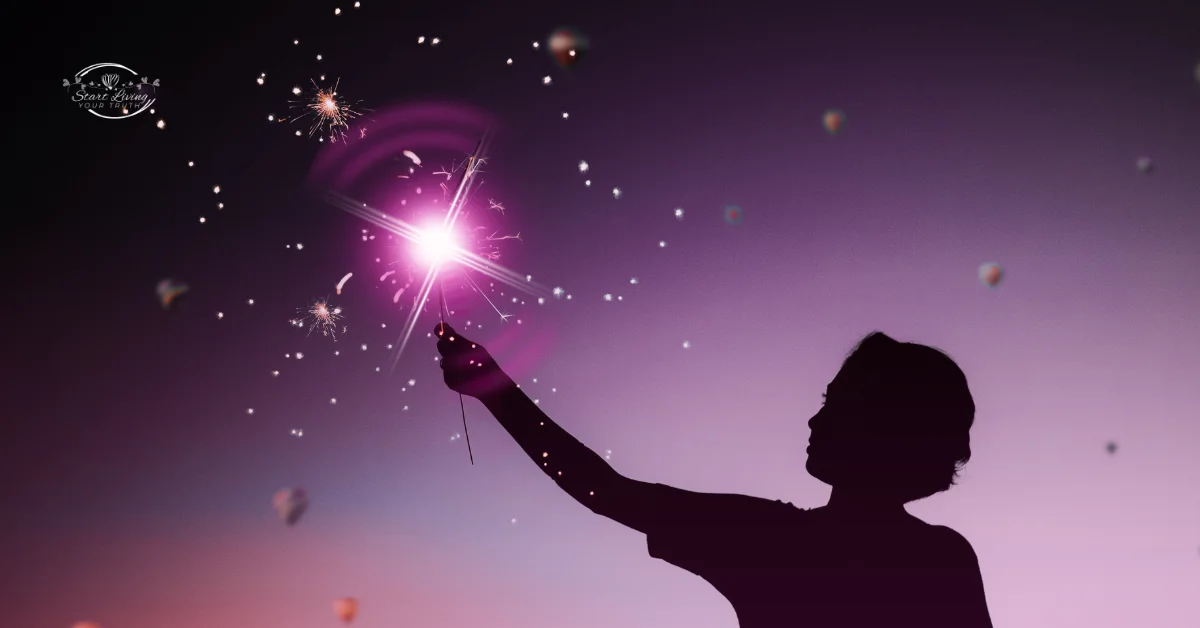 Silhouette holding glowing sparkler against purple sky.
