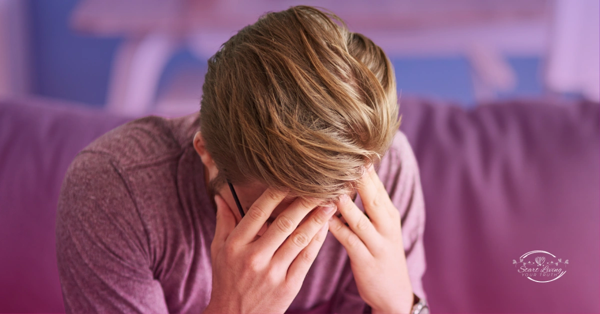 Stressed person with head in hands on couch.