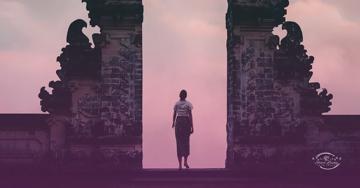 Person standing between ancient stone pillars at sunset