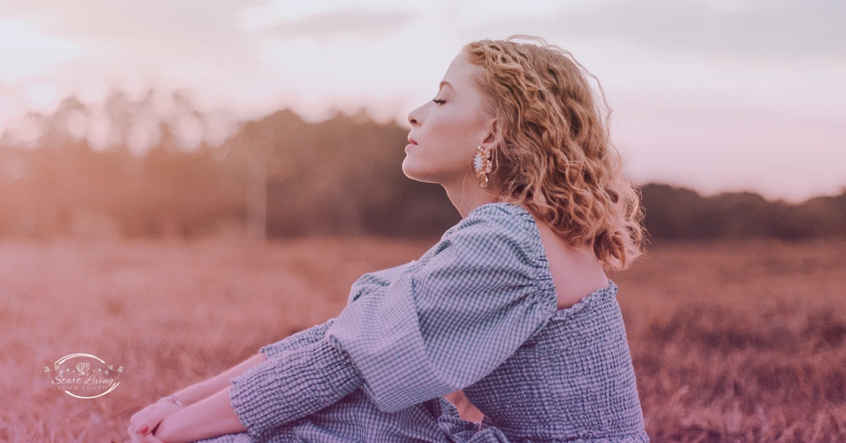 Woman sitting in field at sunset, relaxed.
