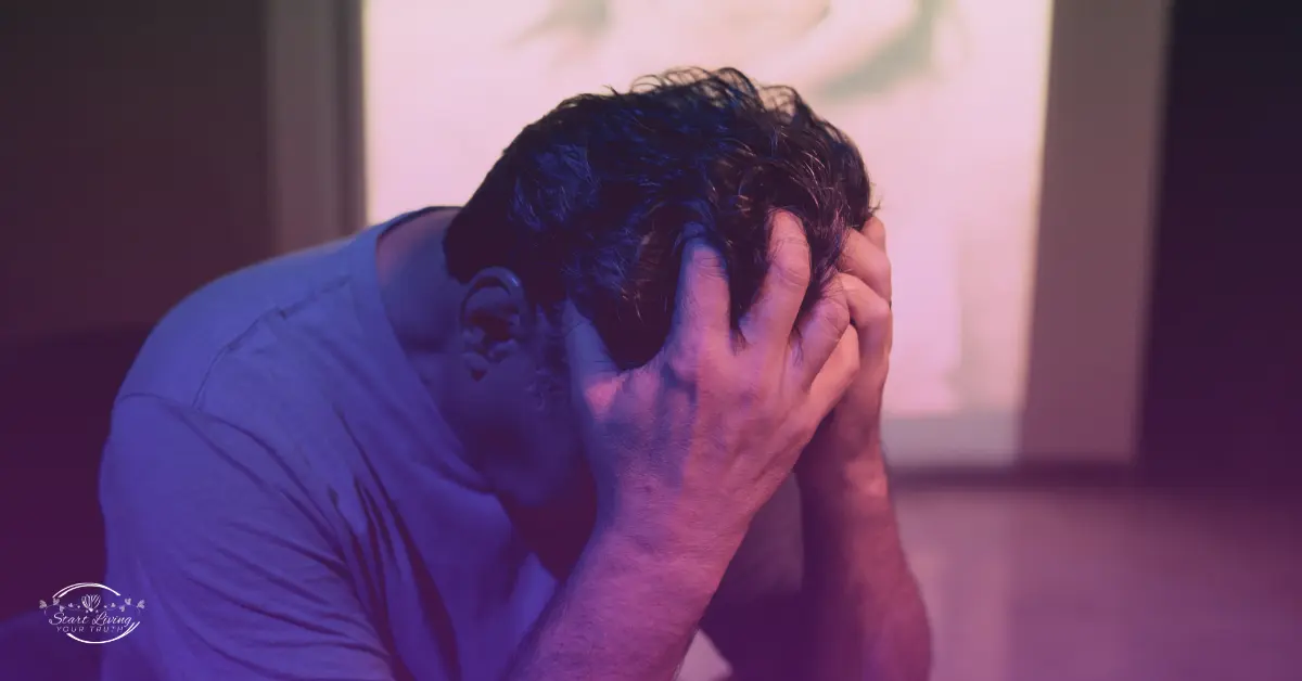 Man sitting, holding head in hands, stressed.